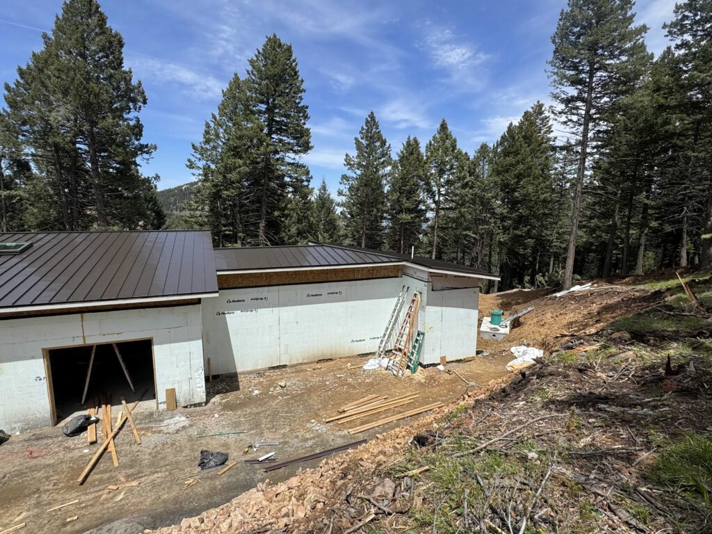 ICF building with a standing-seam metal roof under construction on a wooded Colorado mountain lot