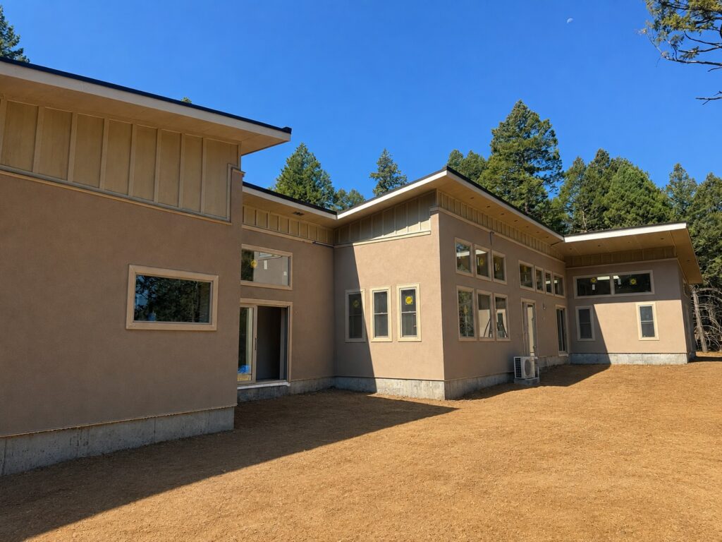 Finished stucco exterior of an ICF mountain home with rows of windows facing the sun