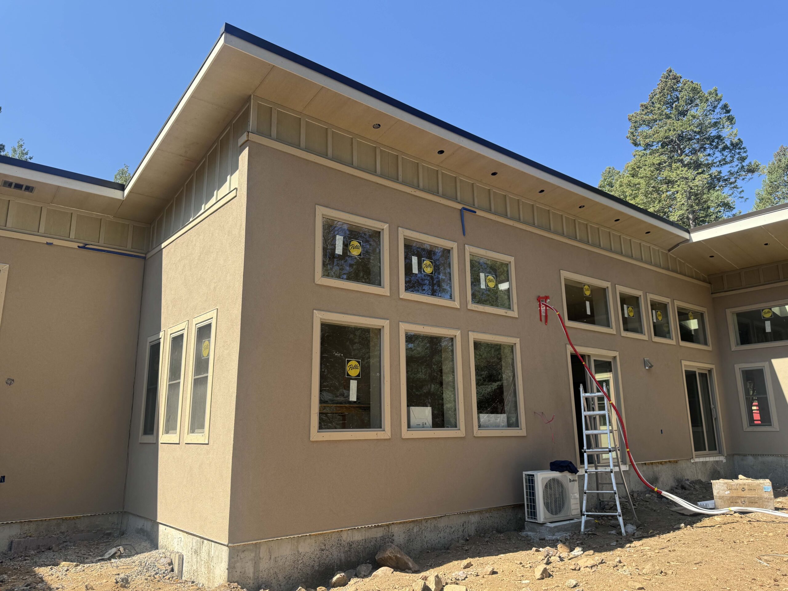 Stucco-finished ICF custom home with large windows on a pine-covered Colorado mountain lot