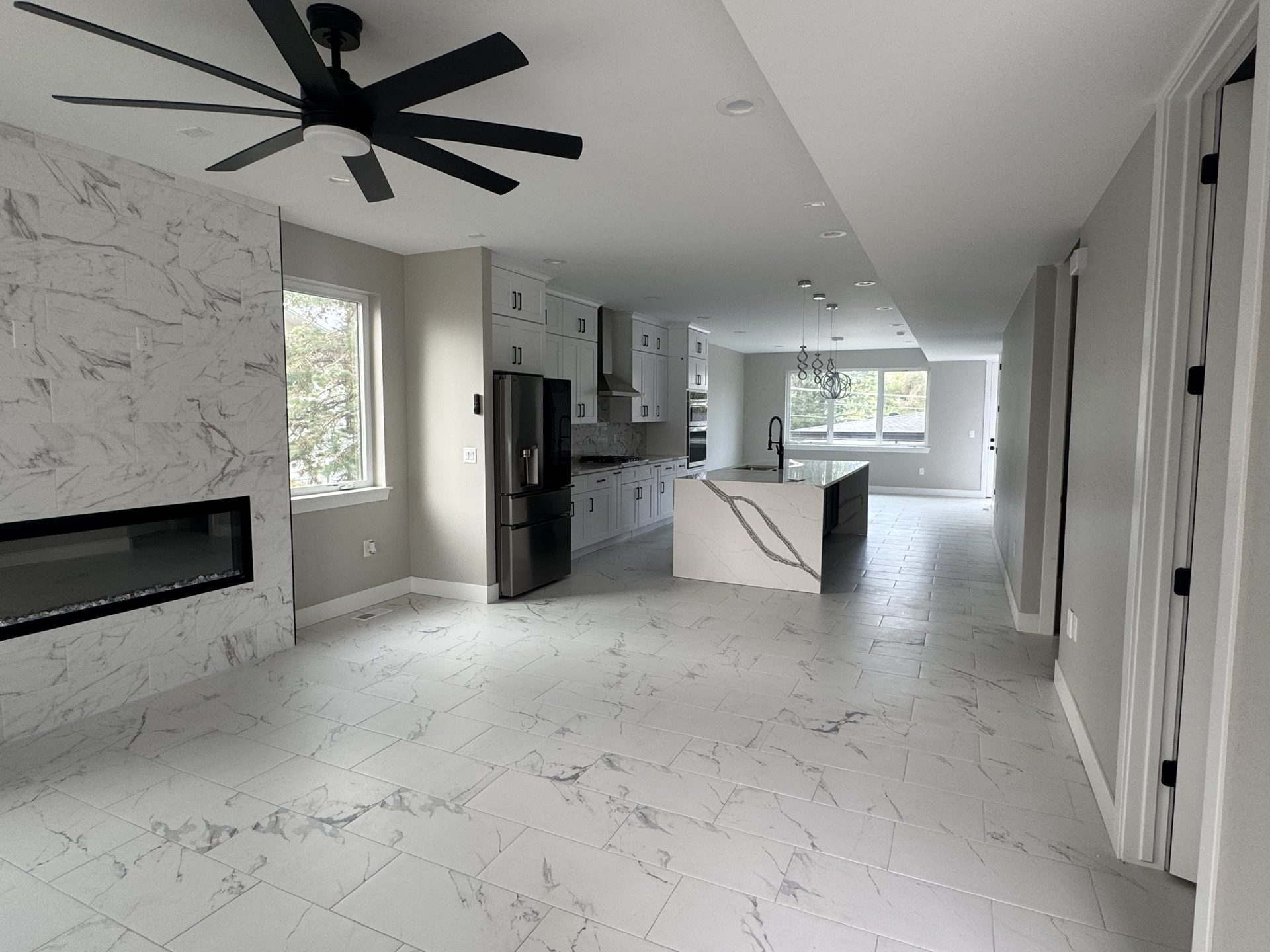 Living room with marble fireplace surround opening to the kitchen in a custom Front Range home